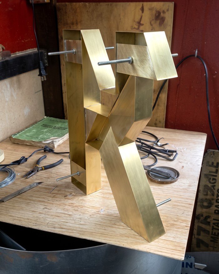 Fabricated metal letter standing on a workbench