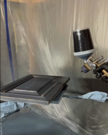Spray gun beside metal panels in a finishing area